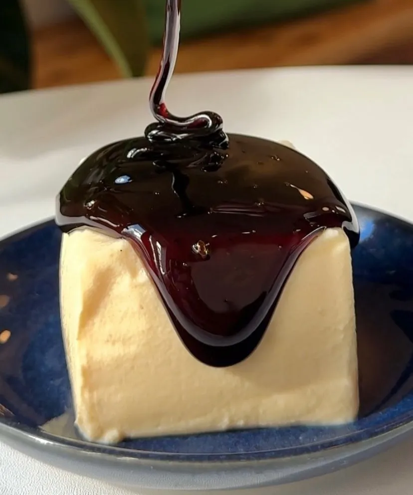 四角いケーキにソースがかけられている様子を捉えた写真です。ソースは、ケーキの上に流れ落ちており、美味しそうな印象を与えます。