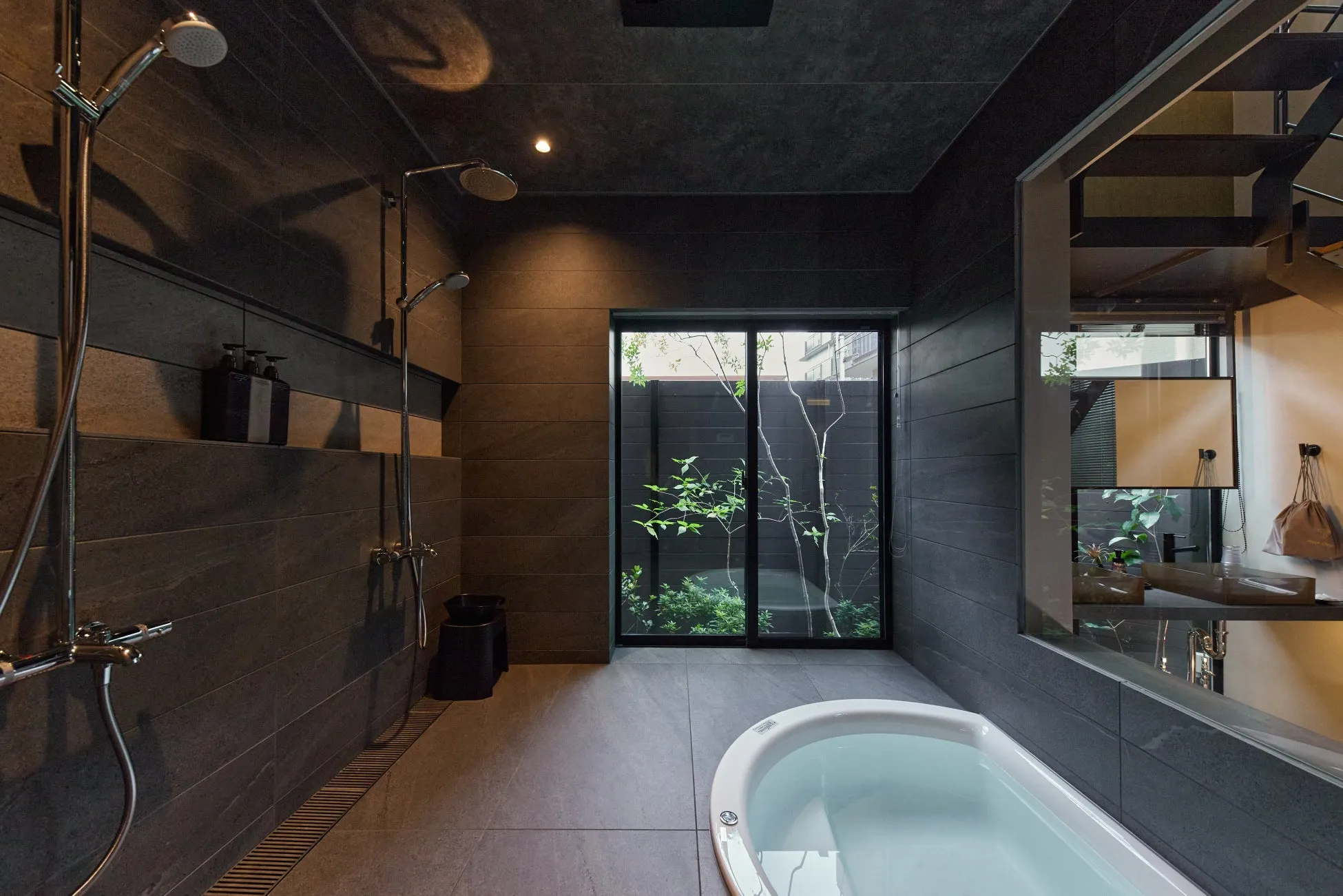 モダンなバスルームのインテリア。黒いタイル張りの壁、シャワーヘッド、バスタブ