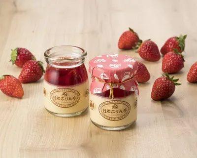 2つのプリンとイチゴが木製のテーブルの上に置かれている写真