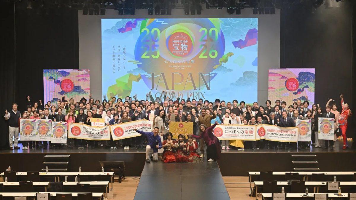 イベントの様子。多くの人々がステージ上でロゴを背景にポーズをとっている。