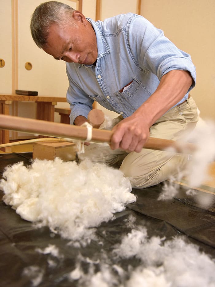 ②竹弓で飛ばしながら繰り綿をほぐす